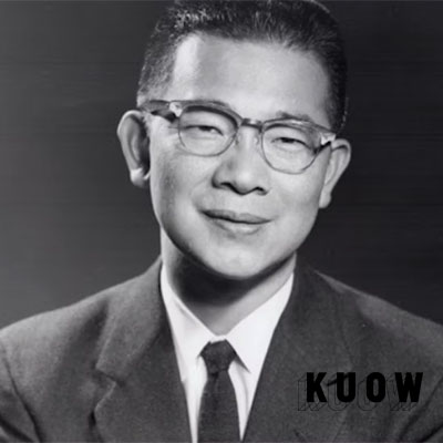 Asian man with glasses on in a suit and tie. 